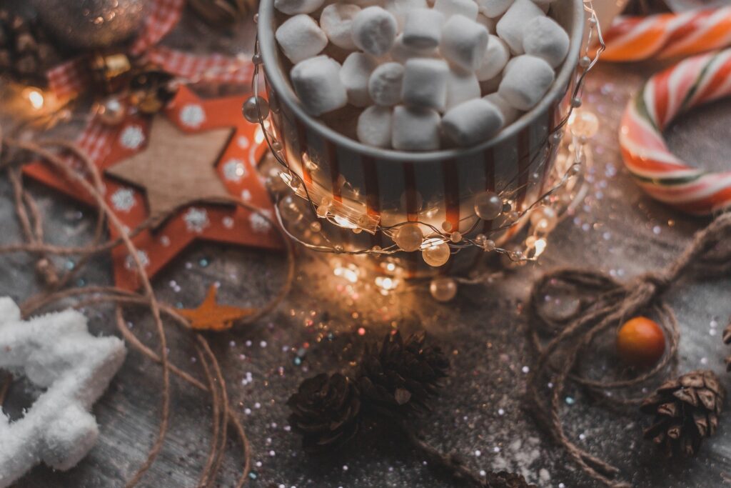 A table full of holiday décor: candies, marshmallows, Christmas lights, ornaments.